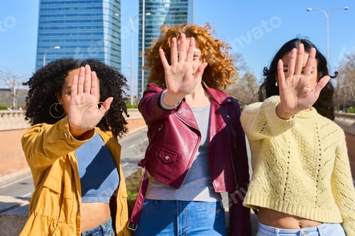 Preview: Three young women showing stop sign with hands in the city