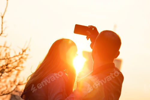 Preview: Young Tourist Couple Using Smart Tablet In Urban City Environment For Taking Photos In Sunset /