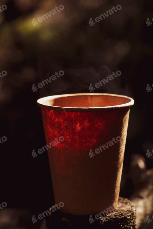 Preview: Disposable paper cup mockup with hot tea stands on a stump against a dark background