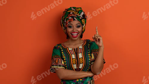 Preview: Inspired pretty black woman in african costume showing eureka gesture