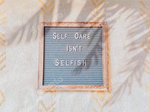 Vorschau: Brieftafel mit Worten „Self Care Isn't Selfish“ auf cremefarbenem Hintergrund mit Palmenschatten