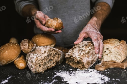 Preview: Baker man holding a rustic organic loaf of bread in his hands