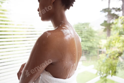 Preview: Rear view of woman wrapped in towel in a bathroom