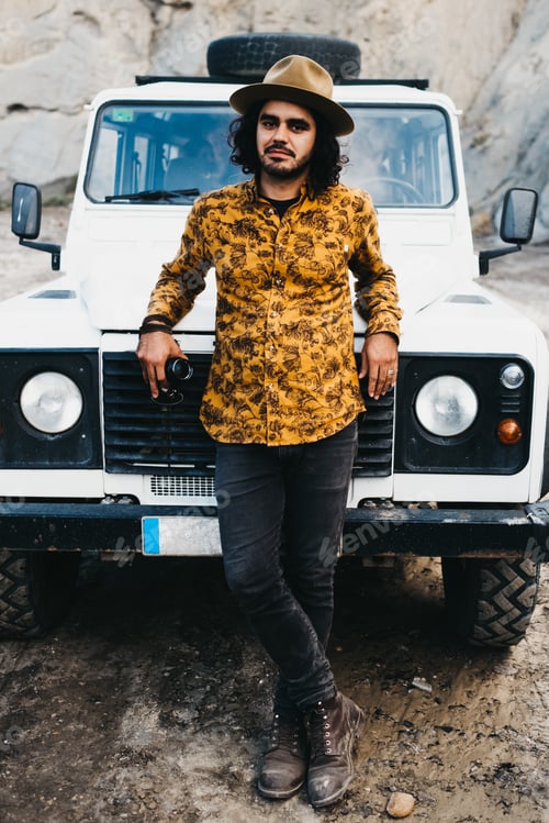 Preview: Stylish man leaning on car hood in canyon