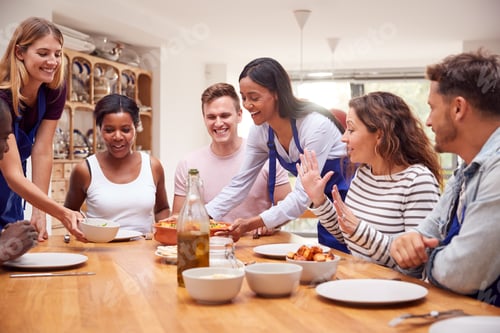 Vista previa: Group Of Men And Women Sitting Around Table Eating Meal They Have Prepared In Kitchen Cookery Class
