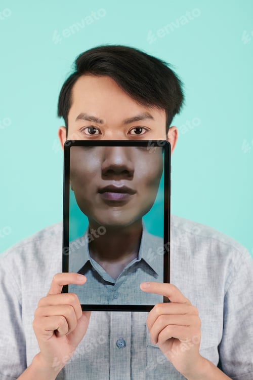 Preview: Young Asian man holding tablet computer with his portrait on screen