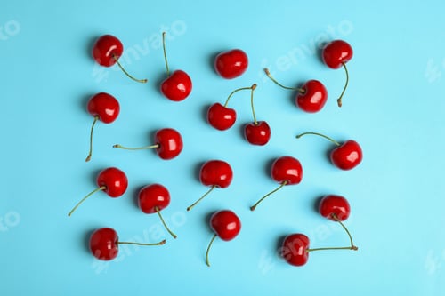 Preview: Many ripe sweet cherries on light blue background, flat lay