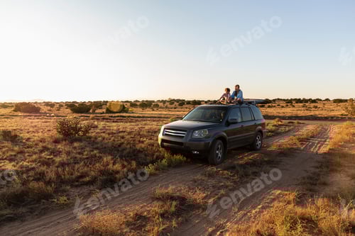 Preview: Teenage girl and her younger brother on top of SUV on desert road