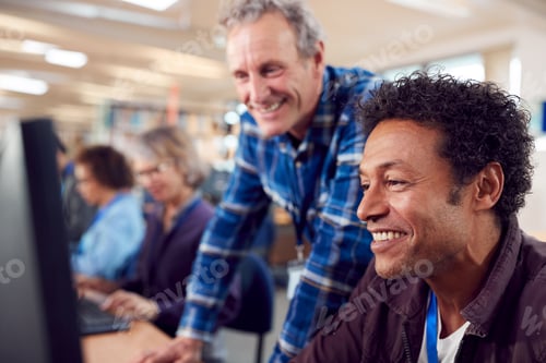 Preview: Teacher With Group Of Mature Adult Students In Class Working At Computers In College Library