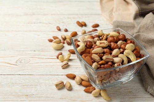 Preview: Bowl with different nuts on white wooden background