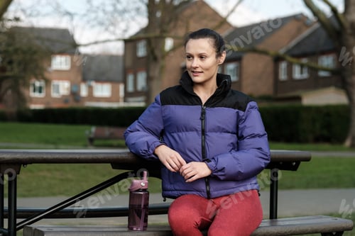 Preview: Caucasian sport female sitting on a bench and resting from exercise.