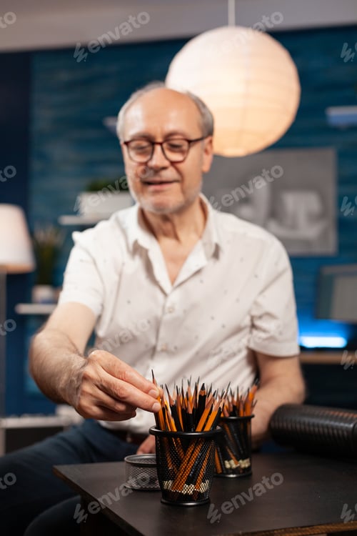 Preview: Selctive focus on elderly man illustrator selecting sharp hb pencil to create black and white