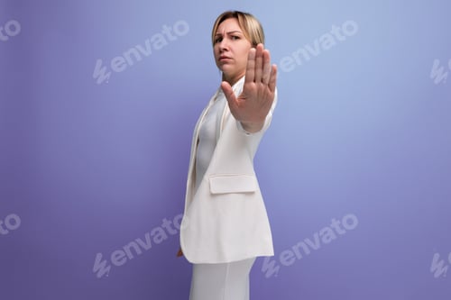 Preview: serious young caucasian blondie lady in an elegant manner shows stop with her hand