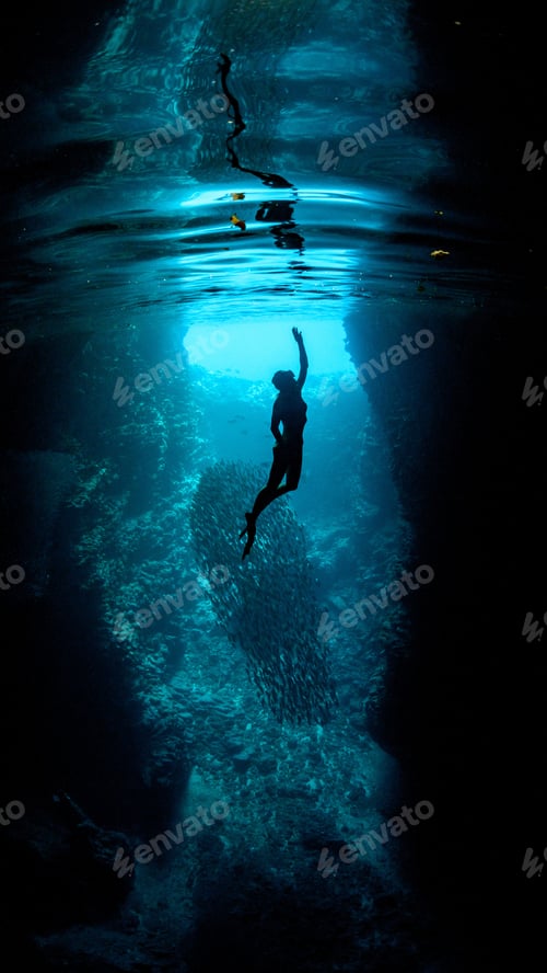 Preview: Underwater vertical shot of a diver reaching toward the surface with one hand