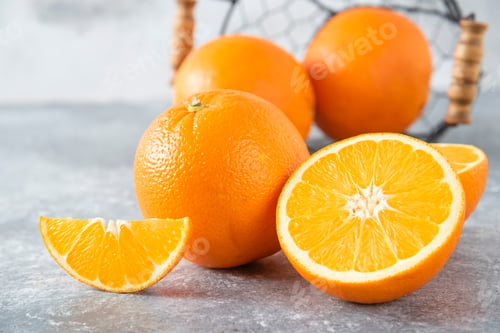 Preview: A metallic black basket full of juicy orange fruit on stone background