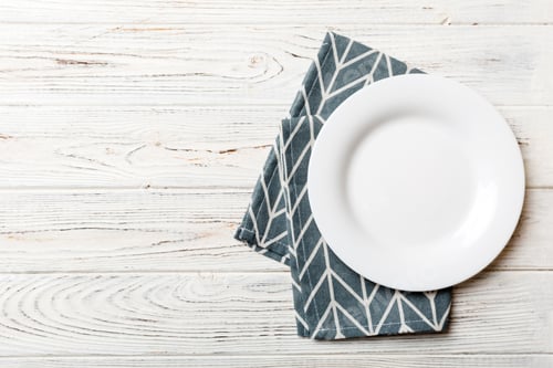 Preview: Top view on colored background empty round white plate on tablecloth for food.