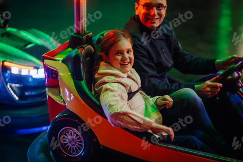 Preview: Father and daughter enjoying bumper cars at amusement park