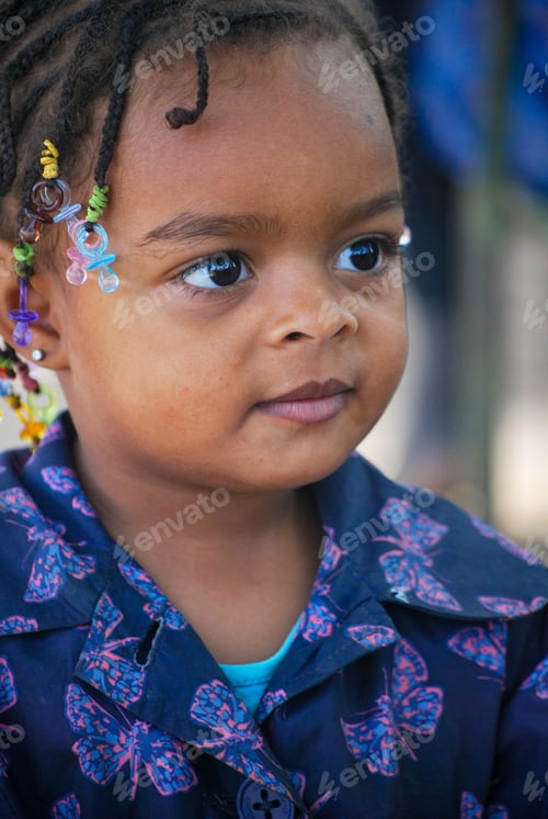 Preview: Portrait of a cute little girl of mixed or black race with braided hair and big bright eyes
