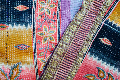 Preview: Close up of a fabric bedspread or throw, with different fabrics appliqued and quilted, a retro style