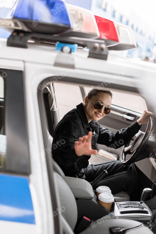 Preview: smiling female police officer sitting in patrol car