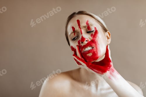 Preview: Portrait of woman with bloody mark on her face. Woman takes by throat on beige background