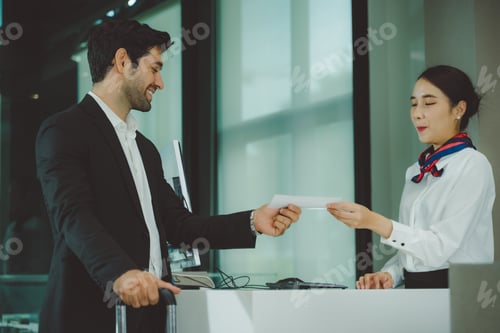 Preview: Business traveler receiving boarding pass from airline staff at airport check-in counter