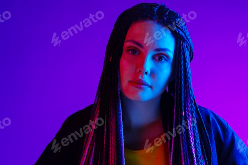 Preview: Fashion portrait of young woman with dreadlocks in neon light