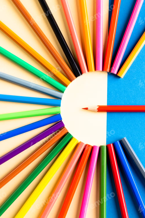Preview: Close up of multi coloured pencils in circle and copy space on blue and yellow background