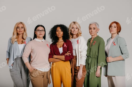 Preview: Group of confident mature women wearing breast cancer ribbons against grey background