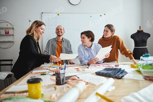 Preview: Friendly designers laughing while working together at the table