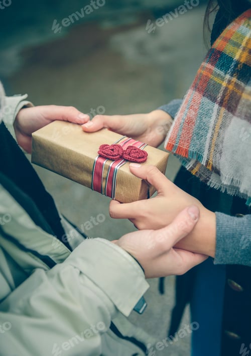 Vista previa: Man hands giving gift box to woman with scarf