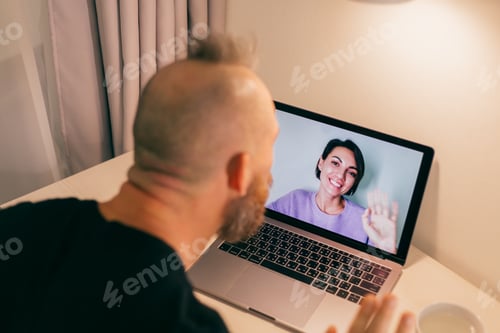 Preview: Man facetime at home, calling his friend wife girlfriend from laptop in bedroom.