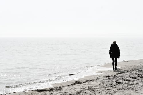 Preview: High key landscape photo of a person from behind walking on the beach