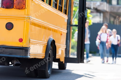 Preview: traditional american school bus with group of students walking blurred on background