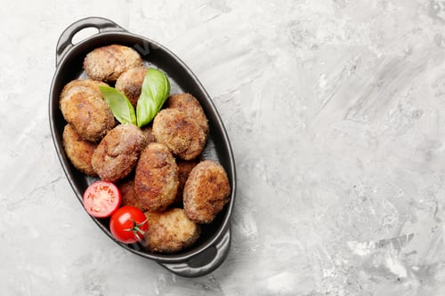 Preview: Tasty meat patties with basil and tomatoes on grey textured table, top view. Space for text