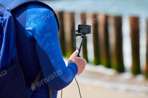 Preview: Male tourist recording video on action video camera, hand holding digital camera, close up