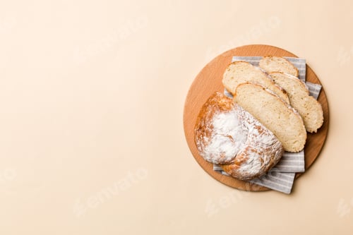 Preview: Freshly baked bread slices on cutting board against white wooden background. top view Sliced bread