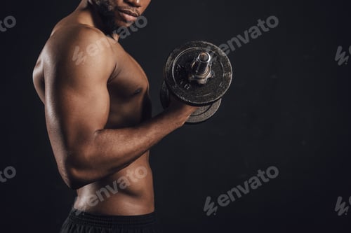 Preview: cropped shot of muscular shirtless african american man exercising with dumbbell isolated on black
