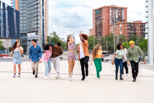 Preview: Happy playful multiethnic group of young friends bonding outdoors
