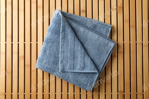 Preview: Fresh blue towel on bamboo background, top view