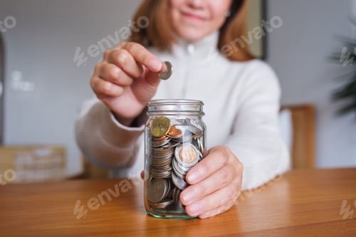 Preview: Woman Saving Money in a Jar on Desk