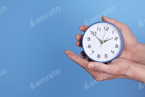 Preview: Man with alarm clock on light blue background, closeup. Space for text