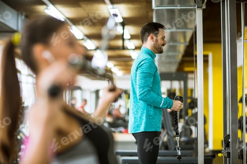 Preview: Young couple exercise bodybuilding exercises in the modern gym