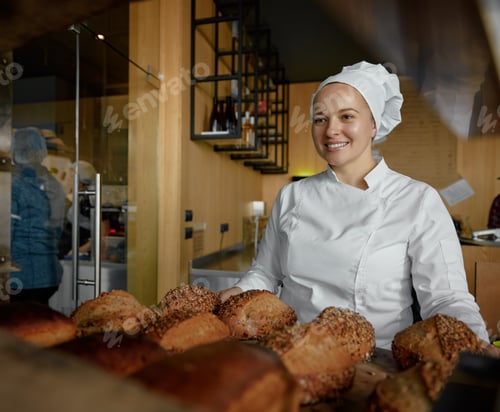 Preview: Portrait of cheerful kind baker saleswoman offering tasty fresh bread