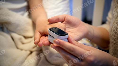 Preview: Mother putting pulse oxymeter on finger of her sick child to measure level of oxygen in blood