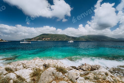 Preview: Crystal clear transparent blue turquoise teal Mediterranean sea water in Fiskardo town. White yacht