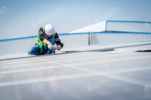 Preview: Male engineer installing or checking the working condition of solar panels on the roof