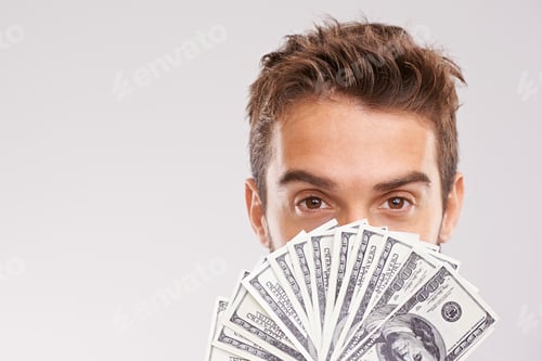 Preview: Ive got money to spare. Studio shot of a businessman holding a fan of money in front of his face.