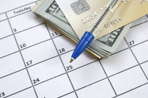 Preview: Pen and credit card on many hundred US dollar bills on calendar page close up