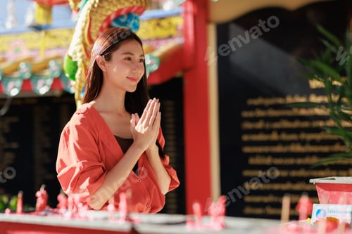 Preview: Young asian woman performing traditional praying gesture at temple
